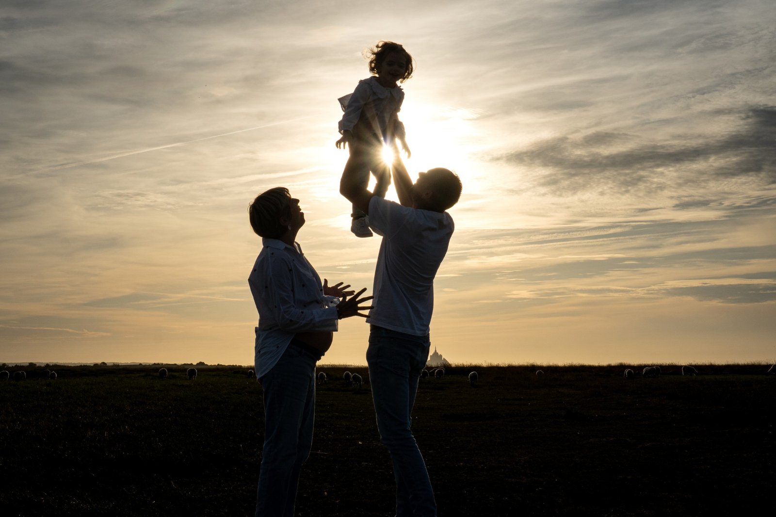 Papa lançant sa fille dans les airs au coucher du soleil