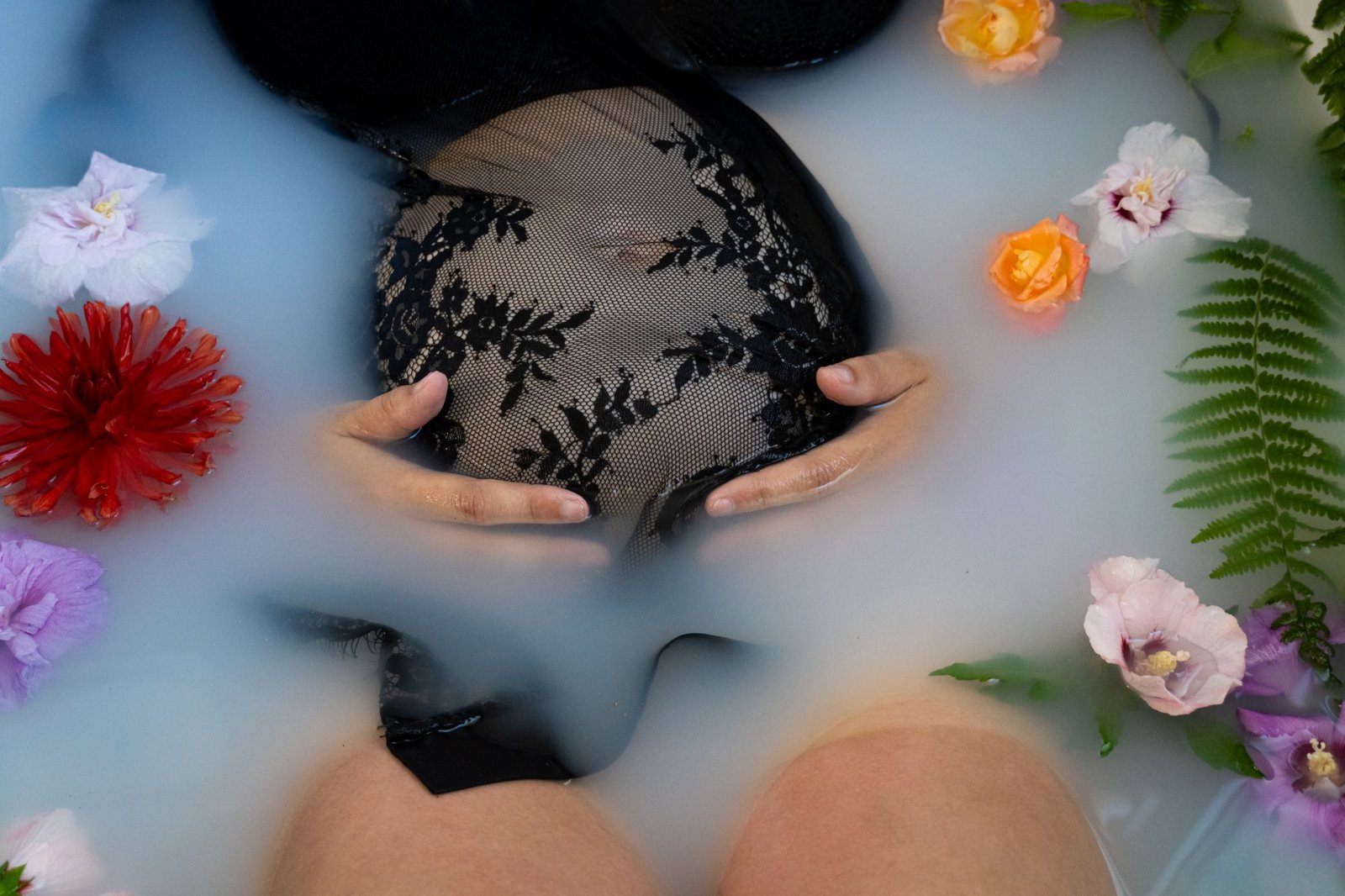 Ventre rond dans un bain de lait entouré de fleurs